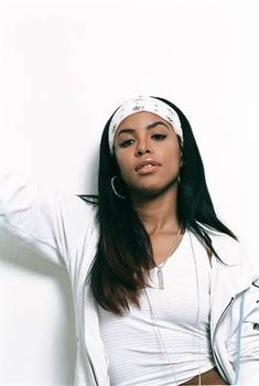 a woman with long hair wearing headband and white shirt posing for the camera while leaning against a wall