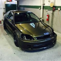 a green car parked in a garage next to another car