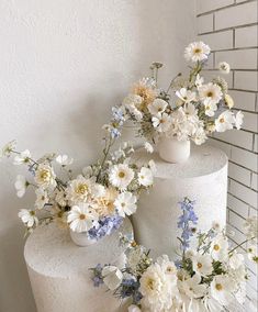 three white vases filled with flowers on top of a cake covered in frosting