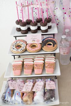 a table topped with donuts and cupcakes on top of trays filled with candy