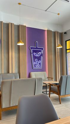 the interior of a restaurant with chairs and tables in front of a neon sign on the wall