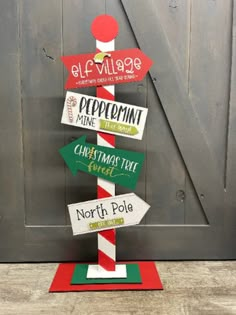 a wooden sign that has some signs on it in front of a barn door with the words elf village, peppermint time, christmas tree, north pole, north pole and north pole