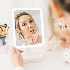 a woman looking at her face in the mirror