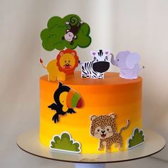 a colorful cake with animals and trees on it's top tier is decorated in yellow, orange, and green