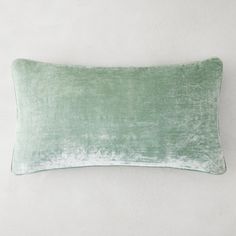 a green velvet pillow on a white wall