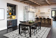 a dining room table and chairs in front of an open kitchen with wooden beams on the ceiling