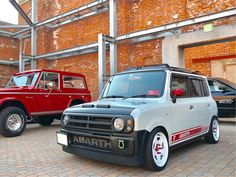 two cars parked next to each other in front of a building with red brick walls