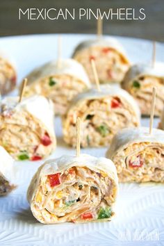 chicken salad wrapped in tortilla with toothpicks on the top and garnished with tomatoes