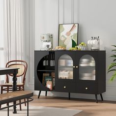 a black cabinet with glass doors in a living room next to a table and chairs