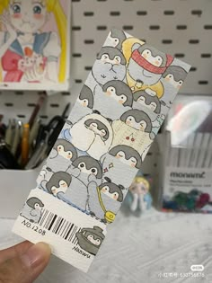 a person holding up a ticket with penguins on it in front of some other items