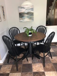 a dining room table with four chairs and a potted plant on top of it