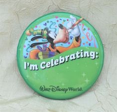 a green button that says i'm celebrating with mickey mouse and pluto on it