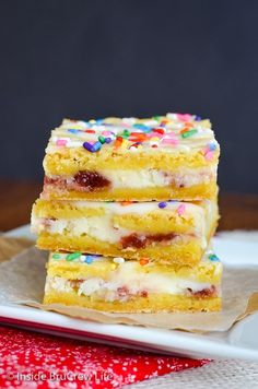 three pieces of cake with sprinkles on a plate next to a red napkin