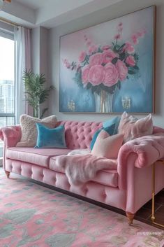 a pink couch in front of a large painting on the wall with flowers painted on it