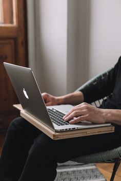 a man sitting in a chair with his laptop on his lap and holding the keyboard