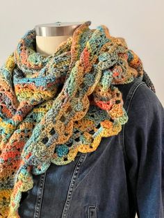 a woman wearing a multicolored crocheted scarf on top of a mannequin