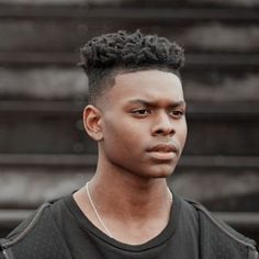 a young man wearing a black t - shirt and standing in front of some stairs