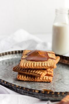 three crackers on a plate with peanut butter and a glass of milk in the background