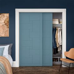 a bedroom with blue walls and white trimmings, an orange chair sits in front of the closet door