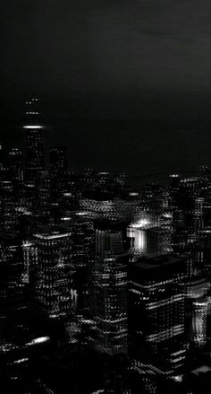 black and white photograph of city lights in the dark night sky, from top of skyscrapers