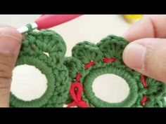 someone is crocheting some green yarn with red thread and scissors in front of them