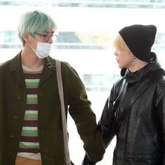 two people with green hair are holding hands and wearing face masks while standing next to each other