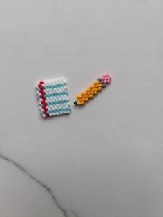 two pieces of beaded crafting sitting on top of a white table next to each other