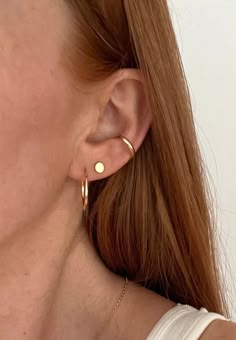 a woman with red hair wearing gold earrings