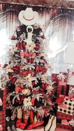 a christmas tree is decorated with red and white plaid ribbon, bows, and cowboy hats