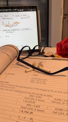 an open notebook sitting on top of a table next to a computer monitor and keyboard