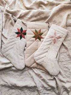 two christmas stockings laying on top of a bed next to each other with red and green stars