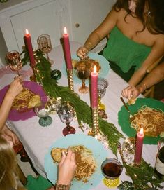 people are sitting at a table with food and candles