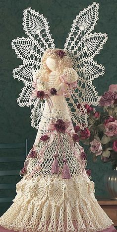 a crocheted angel with flowers in the background