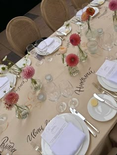 a long table with place settings and flowers on it