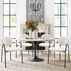 a dining room table with four chairs and a vase filled with flowers on top of it