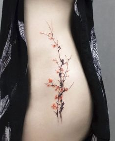 a woman's stomach with a branch tattoo on her side, and flowers growing out of it