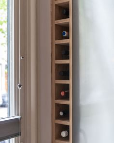 a wooden wine rack next to a window