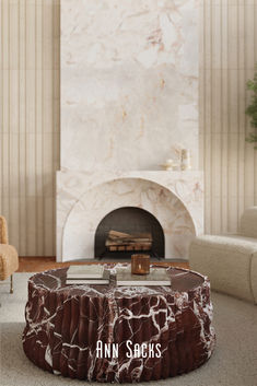 a living room with a marble coffee table and fireplace in the background that reads ann sacks