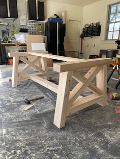 a wooden table sitting in the middle of a room with tools on the floor next to it