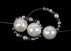 two white pearls and silver beads on a black background