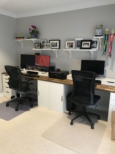 an office with two computer desks and several pictures on the wall