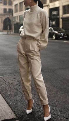 a woman standing on the side of a road wearing high heels and a turtle neck sweater