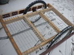 a bike is parked in the snow near a caged area with wheels on it