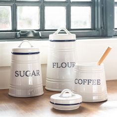 three ceramic sugar jars with the words sugar, flour and coffee written on them in front of a window