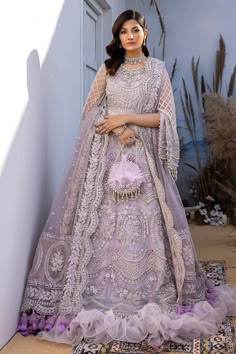 a woman standing in front of a building wearing a purple dress and veil with flowers on it