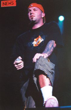 a man with tattoos on his arm is holding a cell phone and standing in front of a microphone