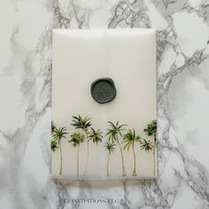 a white marble counter top with palm trees on it and a wax stamp in the middle