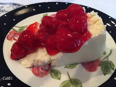 a piece of cheesecake with cherries on it is sitting on a floral plate