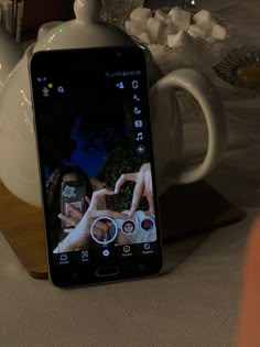 a cell phone sitting on top of a table next to teapots and cups