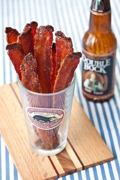 bacon sticks in a glass next to a bottle of beer